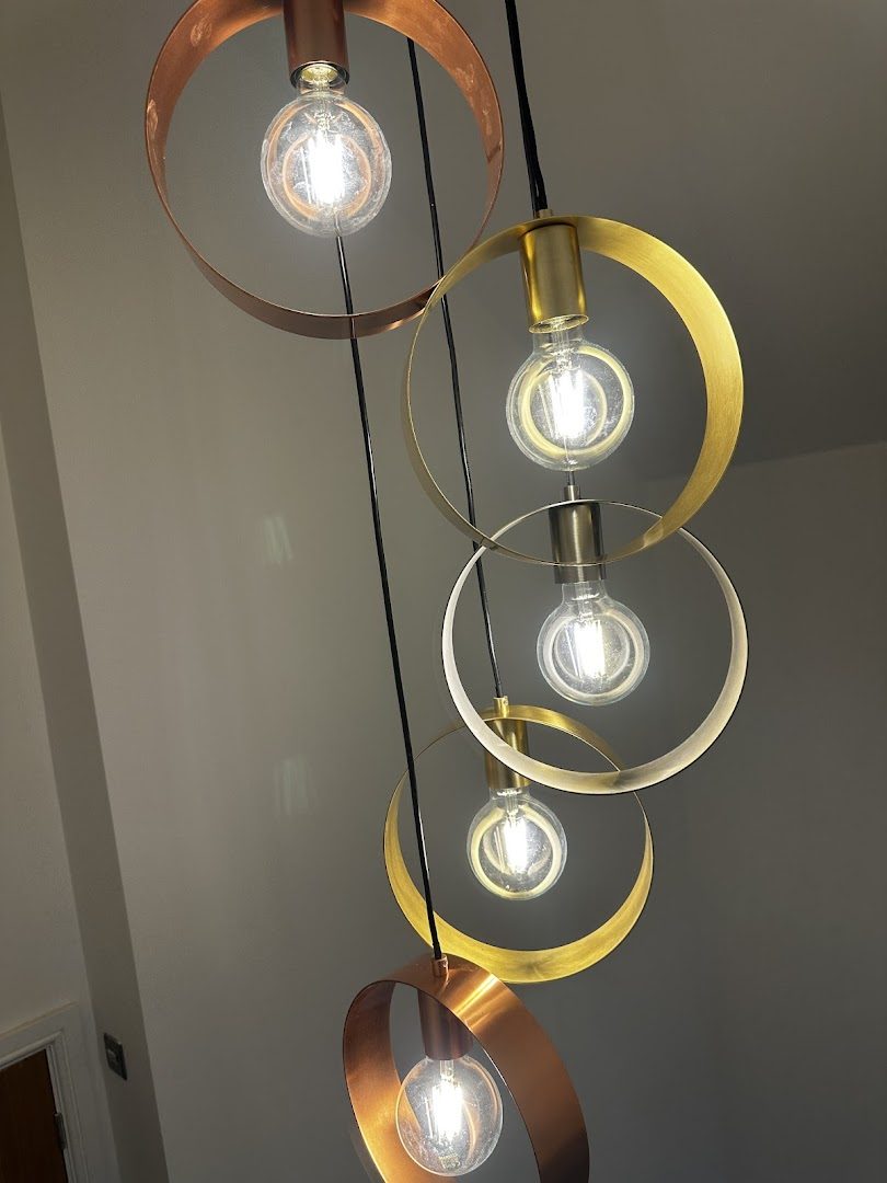 Cluster of brass and copper ring pendants with exposed filament lamps, hung at staggered drops