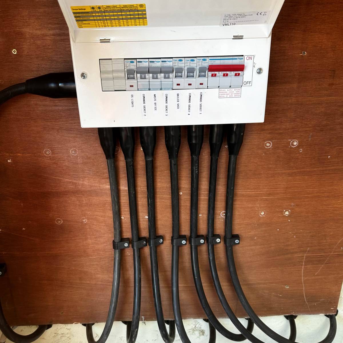 Cabin distribution board with seven separately fused circuits, each labelled and cable-tied to a timber backboard