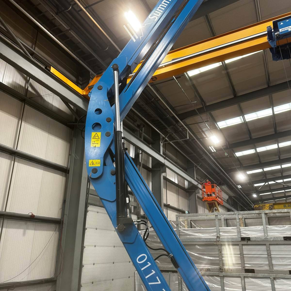 High-level commercial lighting install in a steel-framed warehouse worked from a cherry picker