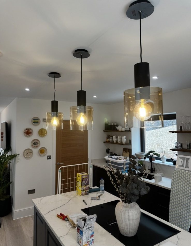 Three black glass pendant lights over a marble kitchen island
