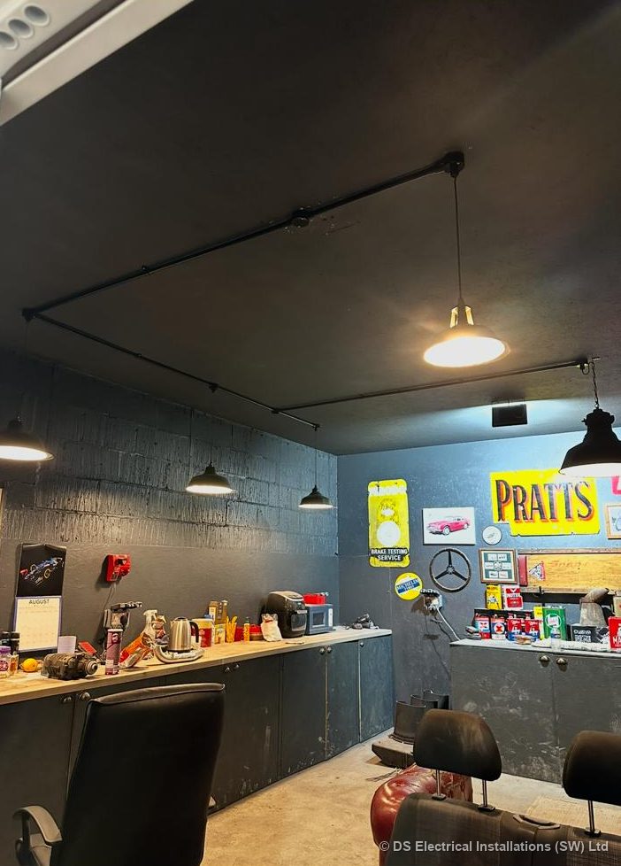 Pendant lights suspended from an exposed black conduit grid in a barber shop
