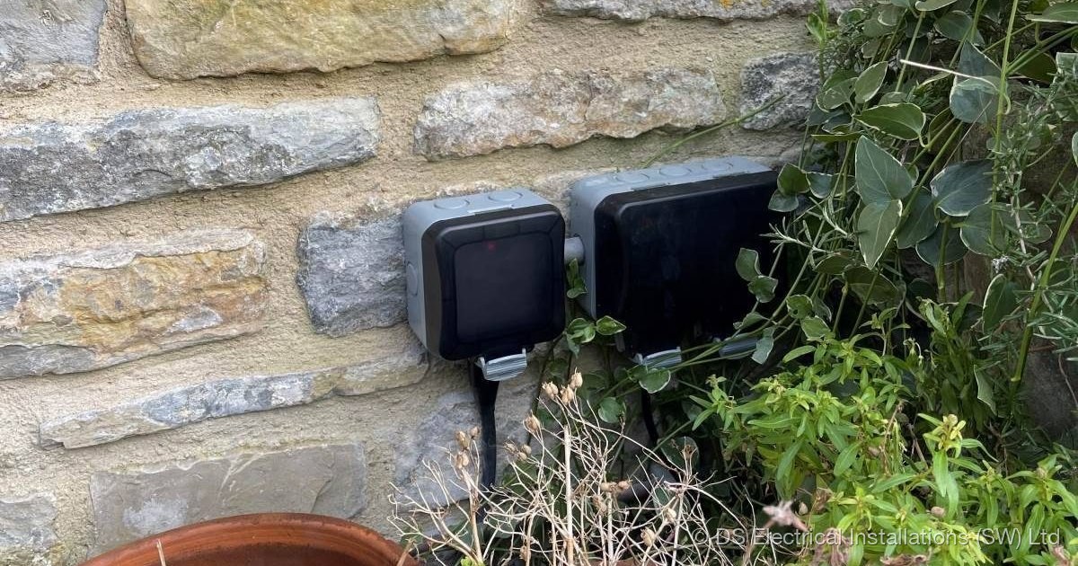Weatherproof outdoor isolators mounted on a stone garden wall by DS Electrical Installations (SW) Ltd