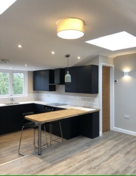 Modern black kitchen with flush ceiling light and skylights