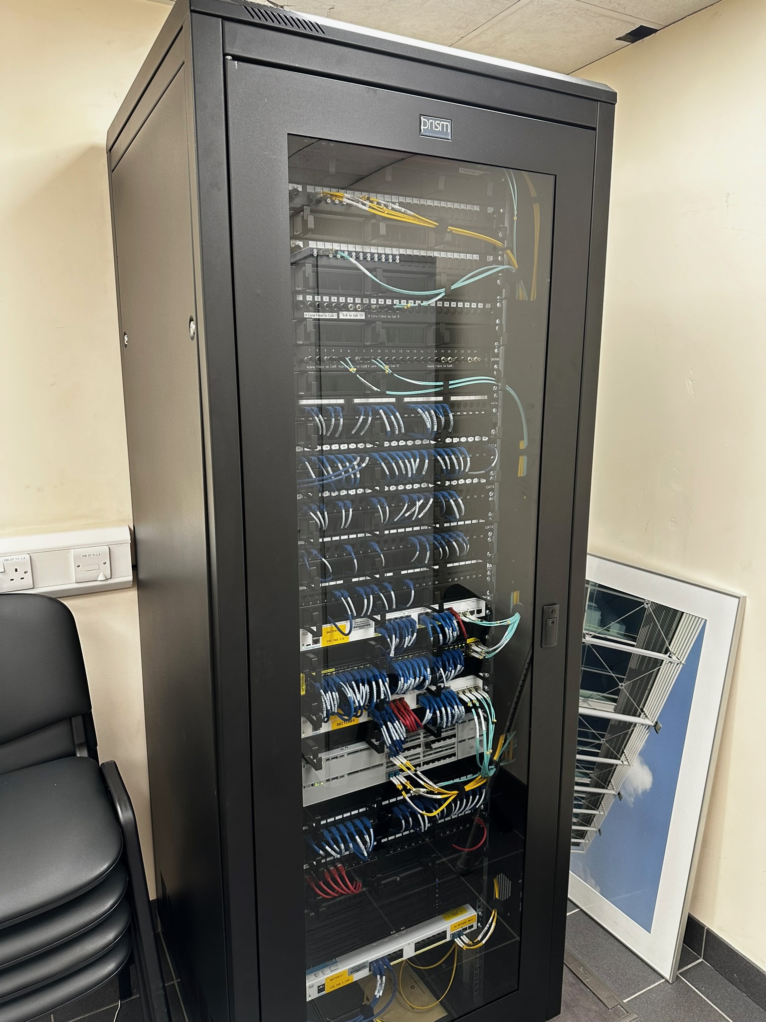 Prism floor-standing comms cabinet — dressed Cat6 patch leads, fibre uplinks, PoE switching, installed by DS Electrical
