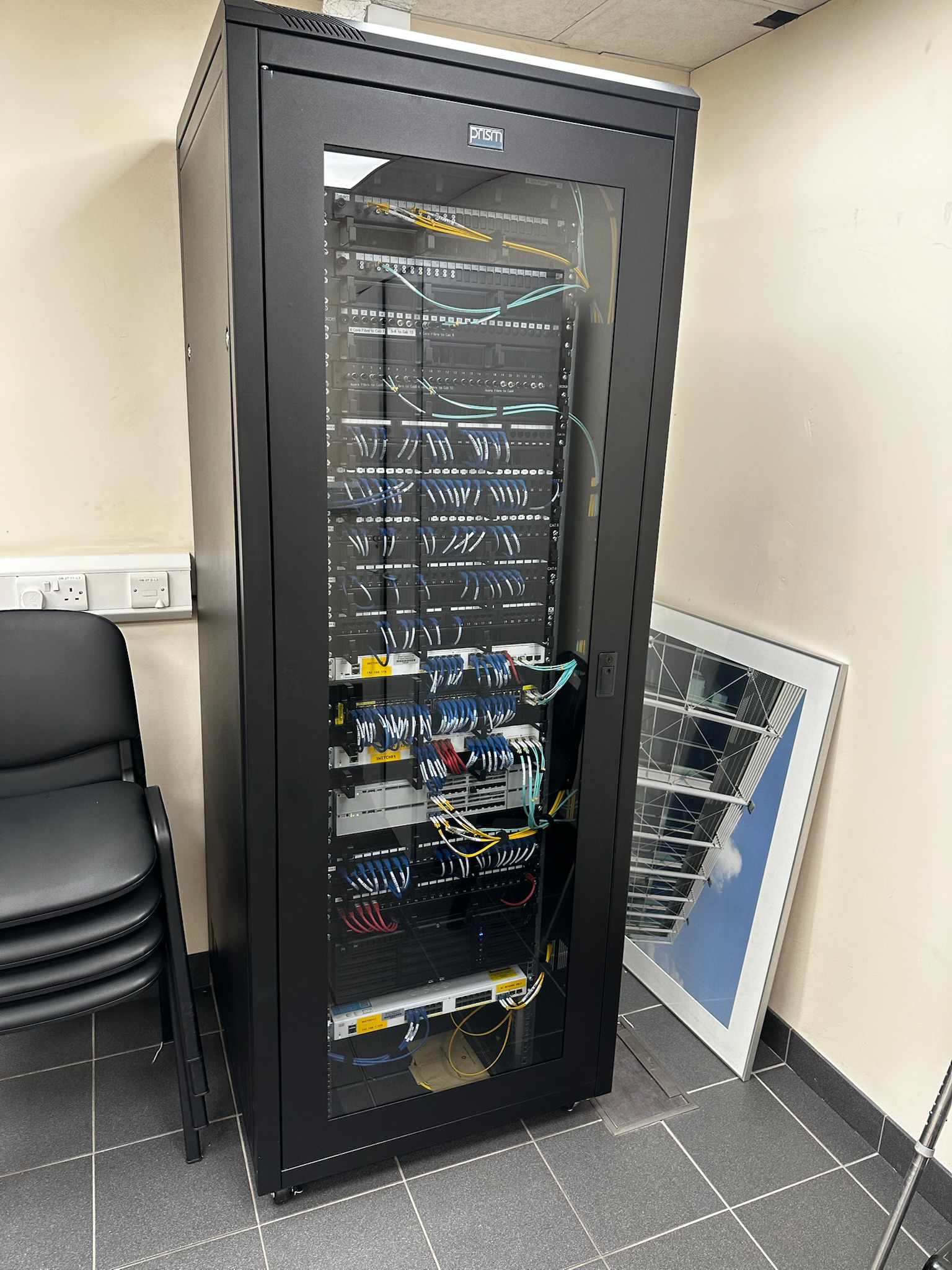 Floor-standing comms cabinet showing complete network infrastructure — Cat6, fibre, PoE switching — installed by DS Electrical