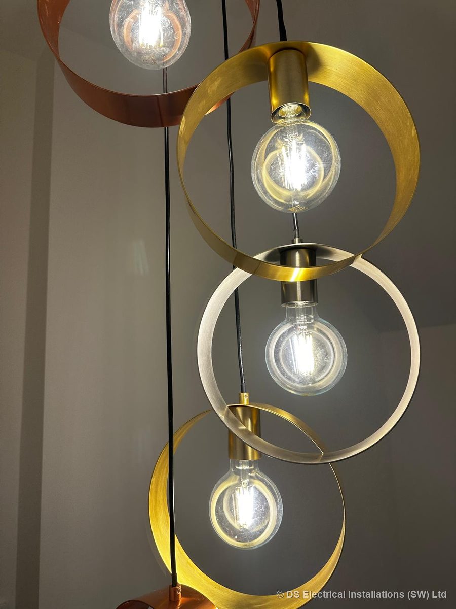 Close-up of brushed brass, copper and nickel ring pendants with globe filament lamps