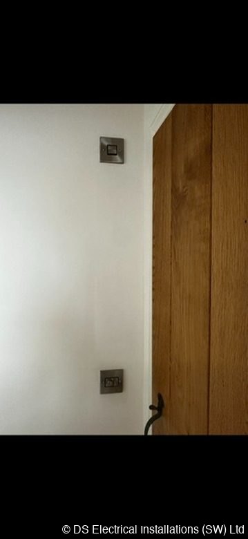 Metal switch plates fitted beside an oak door